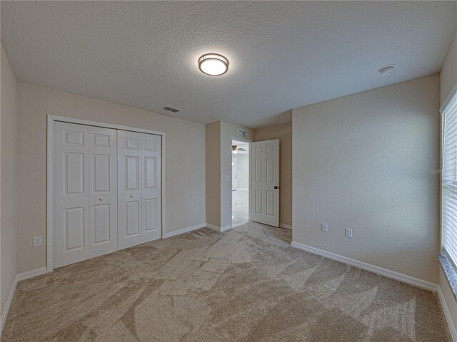1415 Southern Ave, Lakeland, FL 33803 - unfurnished bedroom with carpet flooring, a closet, a textured ceiling, and baseboards
