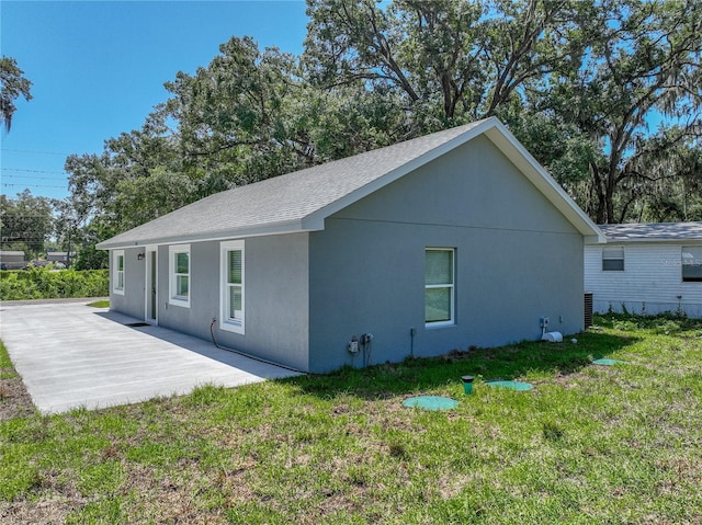 1415 Southern Ave, Lakeland, FL 33803 - rear view of house featuring a lawn, stucco siding, a patio, and a shingled roof