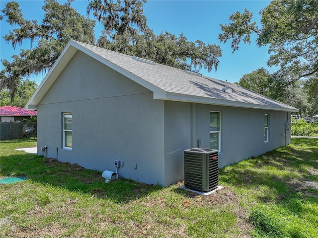 1415 Southern Ave, Lakeland, FL 33803 - view of home's exterior with central AC unit, a lawn, roof with shingles, and stucco siding