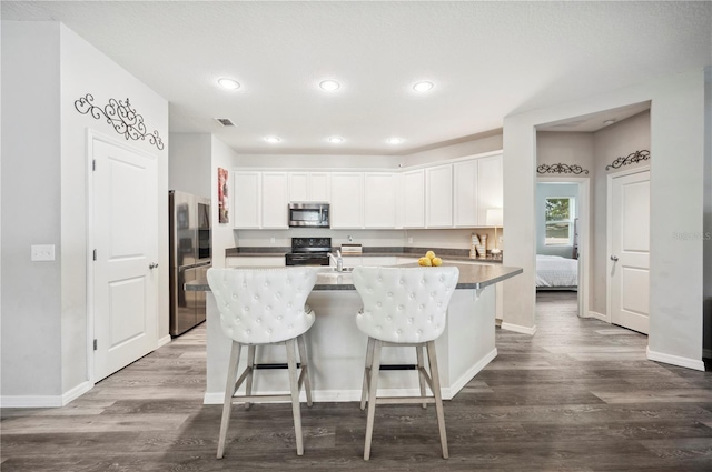 4303 Moon Shadow Loop, Mulberry, FL 33860 - kitchen with appliances with stainless steel finishes, dark wood-type flooring, white cabinets, a kitchen breakfast bar, and recessed lighting