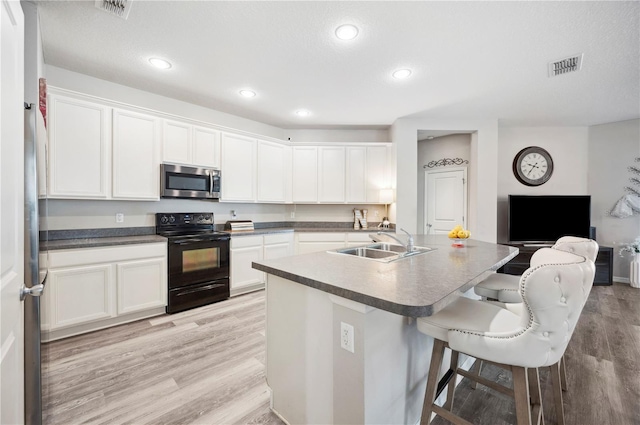 4303 Moon Shadow Loop, Mulberry, FL 33860 - kitchen with black electric range oven, stainless steel microwave, a sink, light wood-style flooring, and a kitchen bar