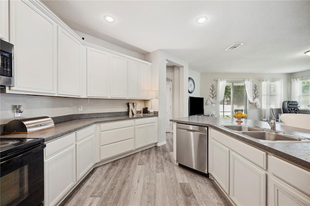 4303 Moon Shadow Loop, Mulberry, FL 33860 - kitchen featuring appliances with stainless steel finishes, a sink, open floor plan, light wood-style floors, and white cabinets
