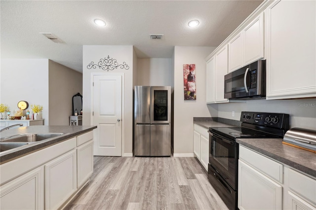 4303 Moon Shadow Loop, Mulberry, FL 33860 - kitchen with smart refrigerator, black / electric stove, dark countertops, light wood-style floors, and white cabinets