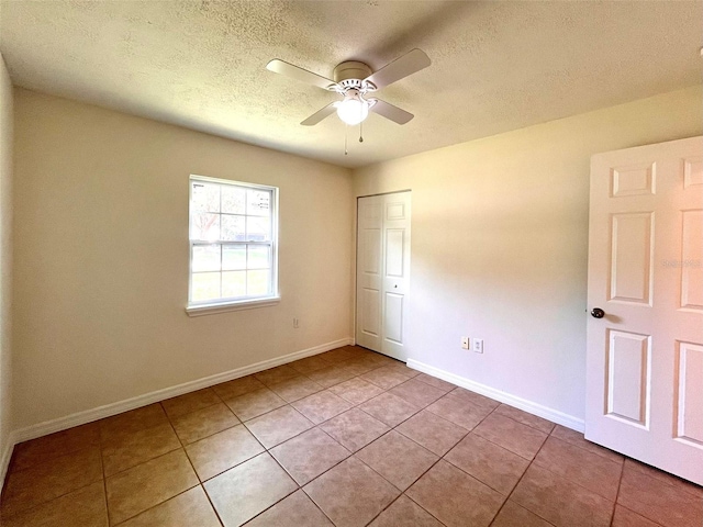 2323 Ridgeview Dr, Lakeland, FL 33810 - unfurnished bedroom featuring light tile patterned floors, a textured ceiling, baseboards, and ceiling fan