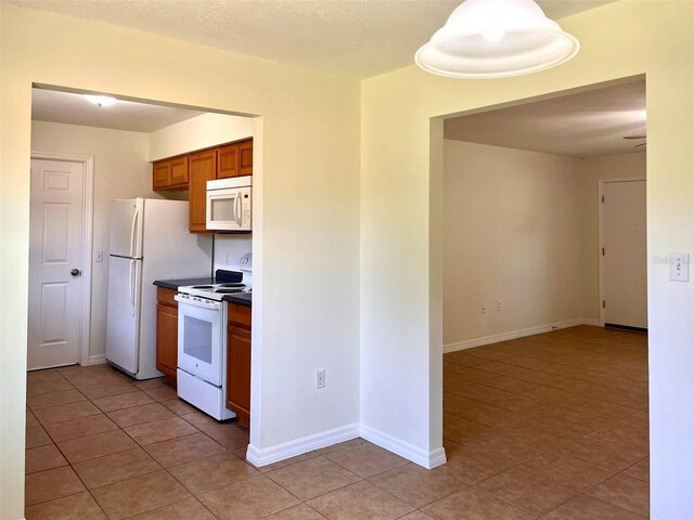 2323 Ridgeview Dr, Lakeland, FL 33810 - kitchen with white appliances, light tile patterned flooring, brown cabinetry, dark countertops, and baseboards