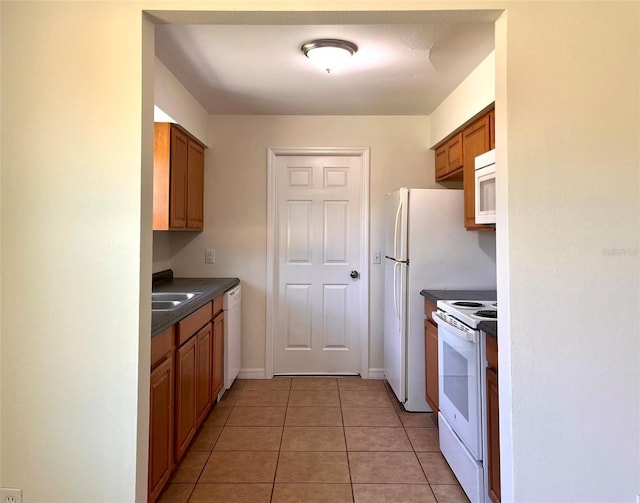 2323 Ridgeview Dr, Lakeland, FL 33810 - kitchen featuring white appliances, dark countertops, light tile patterned floors, brown cabinetry, and a sink