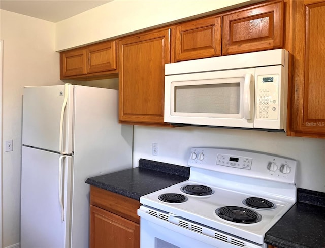 2323 Ridgeview Dr, Lakeland, FL 33810 - kitchen featuring white appliances, brown cabinets, and dark countertops