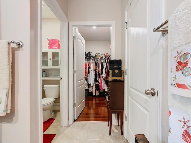 bathroom featuring toilet, tile patterned floors, and a walk in closet