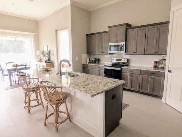 7919 Lake James Blvd, Lakeland, FL 33810 - kitchen featuring appliances with stainless steel finishes, a sink, a kitchen breakfast bar, light stone counters, and a kitchen island with sink