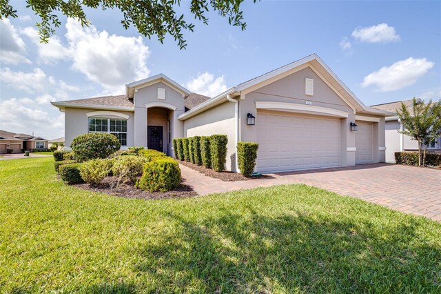 3136 Langdon Ln, Winter Haven, FL 33884 - view of front facade featuring stucco siding, decorative driveway, an attached garage, and a front lawn