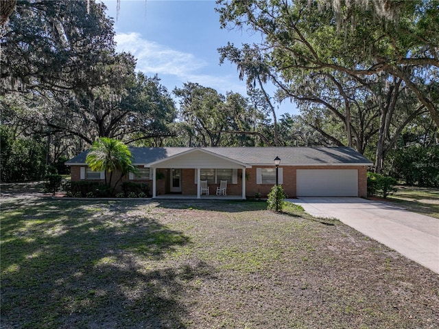 ranch-style house with covered porch, an attached garage, concrete driveway, a front lawn, and brick siding