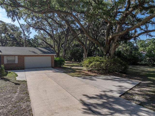 view of side of property featuring a garage, driveway, and brick siding
