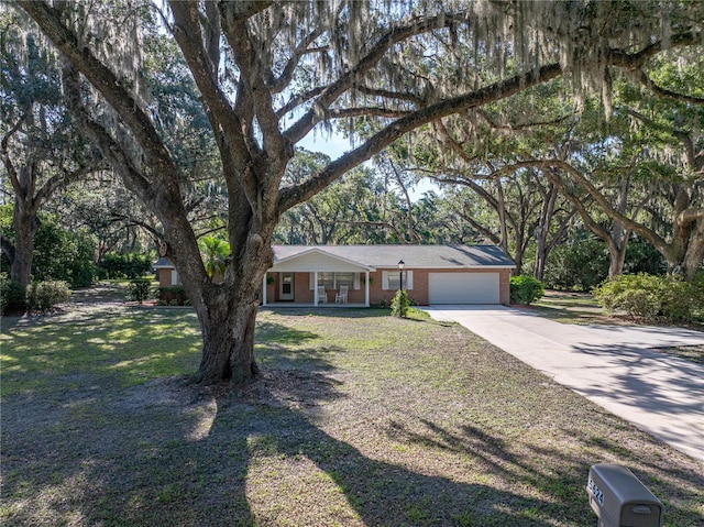 ranch-style house with an attached garage, concrete driveway, covered porch, brick siding, and a front lawn