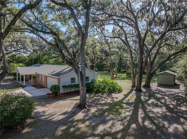 view of yard featuring driveway, a shed, an outbuilding, and view of scattered trees
