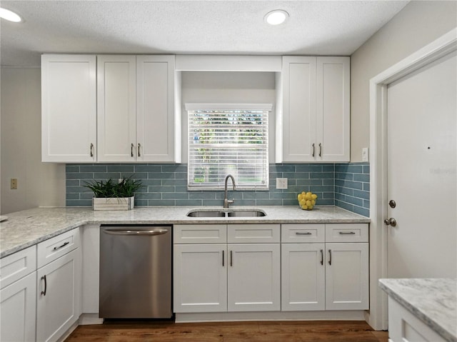 kitchen with a sink, dishwasher, backsplash, white cabinetry, and light stone counters