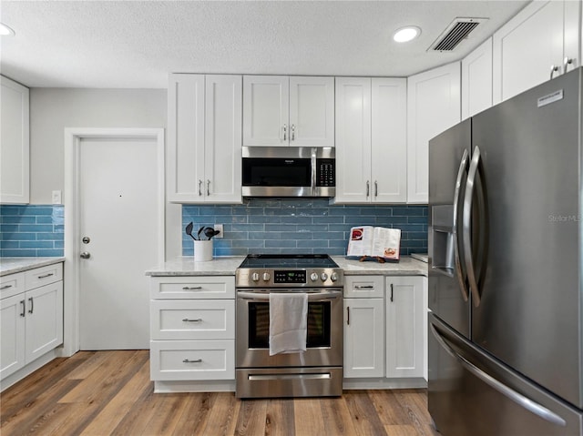 kitchen featuring appliances with stainless steel finishes, white cabinetry, tasteful backsplash, wood finished floors, and recessed lighting