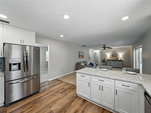 kitchen featuring stainless steel appliances, open floor plan, white cabinetry, ceiling fan, and light wood-style floors