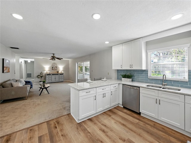 kitchen with a sink, dishwasher, open floor plan, a peninsula, and white cabinetry