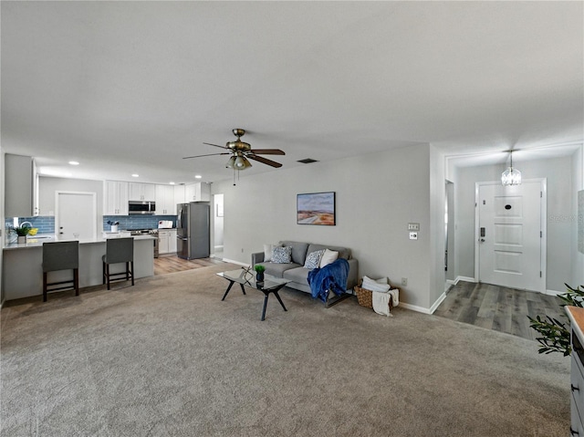 living room featuring light colored carpet, recessed lighting, baseboards, and ceiling fan