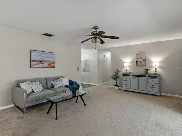 living area featuring baseboards, light colored carpet, and ceiling fan