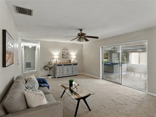 carpeted living room with ceiling fan, baseboards, and a textured ceiling