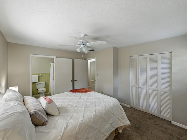 carpeted bedroom with a closet, baseboards, ensuite bath, and a ceiling fan