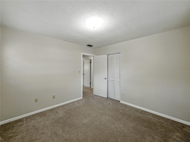 unfurnished room with carpet floors, baseboards, and a textured ceiling