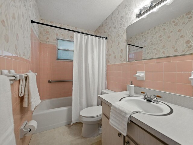 bathroom featuring wallpapered walls, tile walls, toilet, vanity, and shower / bath combo