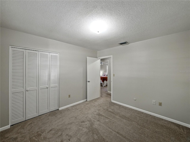 unfurnished bedroom with carpet, a textured ceiling, a closet, and baseboards
