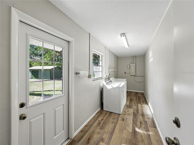clothes washing area featuring washing machine and clothes dryer, wood finished floors, a textured ceiling, electric panel, and baseboards