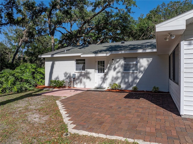rear view of house with a patio area and a shingled roof