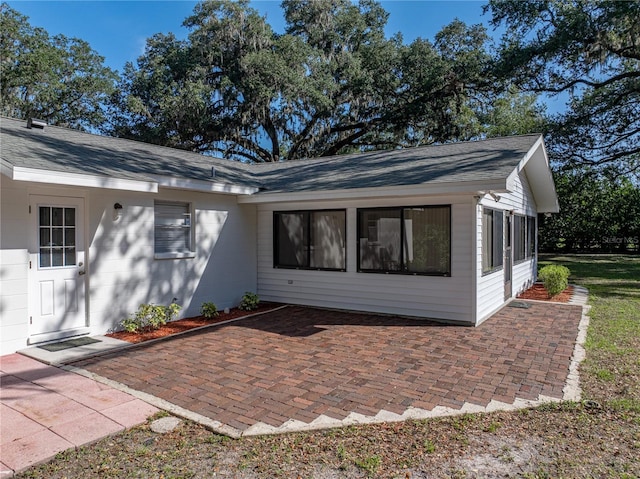 back of property featuring a patio area and a shingled roof