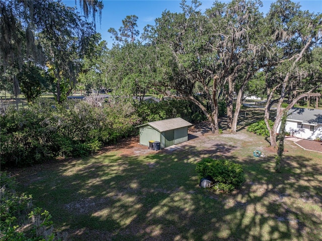 view of grassy yard with an outbuilding and view of wooded area