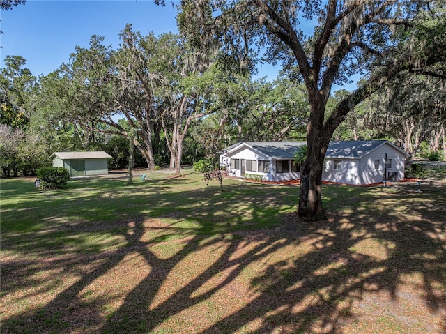 view of green lawn with view of wooded area