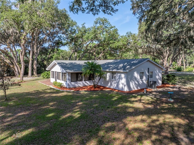 view of front facade featuring a front yard, view of scattered trees, and a shingled roof