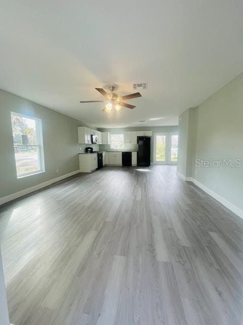 1329 Tom Watson Rd, Lakeland, FL 33801 - unfurnished living room featuring baseboards, a ceiling fan, and light wood-style flooring