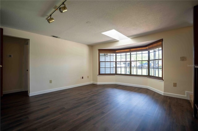 1920 Indian Trails Ct, Lakeland, FL 33813 - empty room with a skylight, dark wood-style floors, baseboards, a textured ceiling, and track lighting