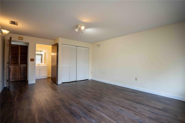 1920 Indian Trails Ct, Lakeland, FL 33813 - unfurnished bedroom featuring dark wood finished floors, a textured ceiling, baseboards, a closet, and connected bathroom