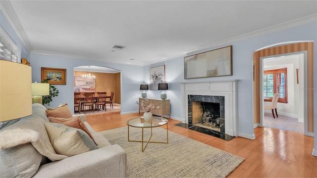 323 E Belvedere St, Lakeland, FL 33803 - living area with ornamental molding, a chandelier, arched walkways, wood finished floors, and a fireplace