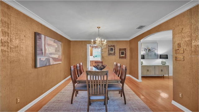 323 E Belvedere St, Lakeland, FL 33803 - dining area featuring wood finished floors, a chandelier, arched walkways, crown molding, and baseboards