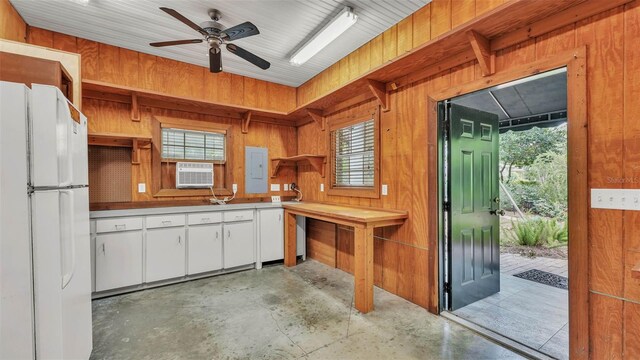 323 E Belvedere St, Lakeland, FL 33803 - kitchen with freestanding refrigerator, open shelves, electric panel, concrete floors, and wood walls