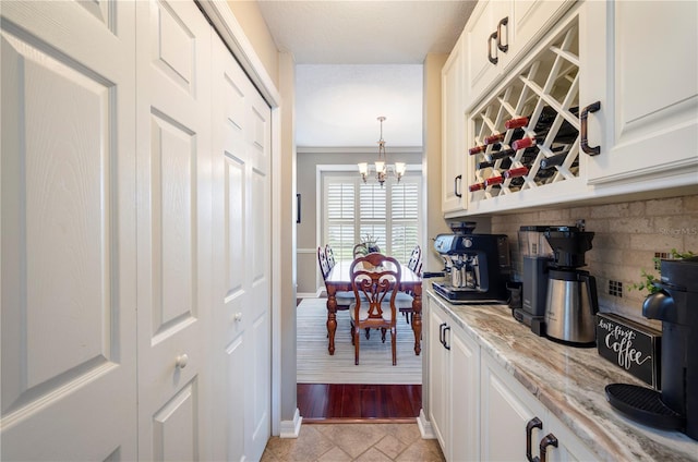 5425 Charlin Ave, Lakeland, FL 33810 - kitchen with tasteful backsplash, light stone counters, white cabinetry, and a chandelier