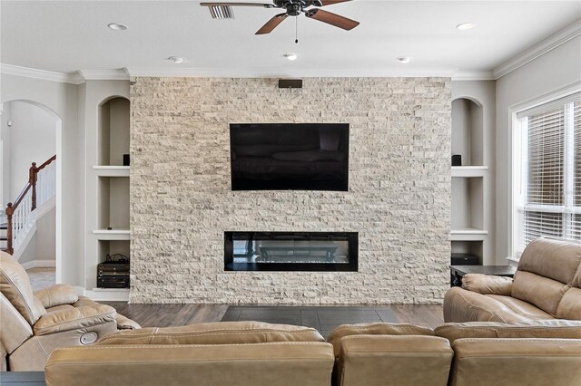 6542 Eagle Ridge Way, Lakeland, FL 33813 - living room with built in features, wood finished floors, a ceiling fan, ornamental molding, and a stone fireplace