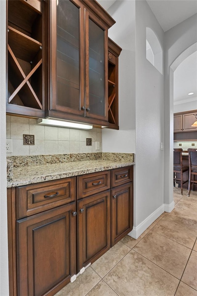 6542 Eagle Ridge Way, Lakeland, FL 33813 - bar featuring light tile patterned floors, decorative backsplash, arched walkways, and baseboards