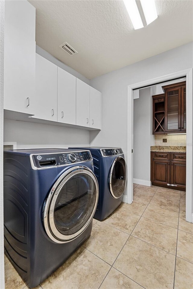 6542 Eagle Ridge Way, Lakeland, FL 33813 - laundry room featuring washing machine and dryer, cabinet space, a textured ceiling, light tile patterned floors, and baseboards