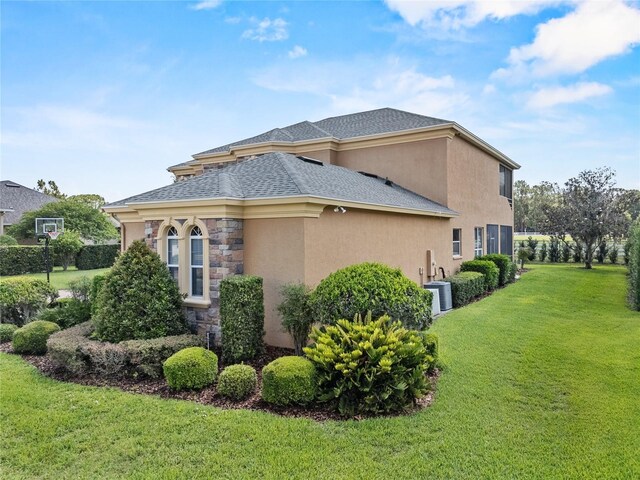 6542 Eagle Ridge Way, Lakeland, FL 33813 - view of property exterior with a yard, stucco siding, stone siding, and roof with shingles
