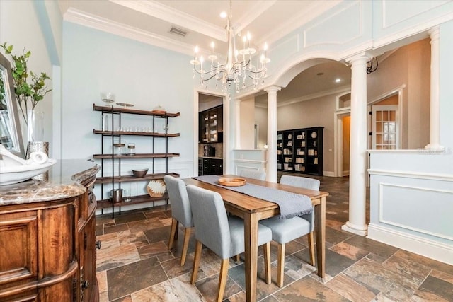 6357 Ashley Dr, Lakeland, FL 33813 - dining room featuring ornate columns, stone tile flooring, ornamental molding, arched walkways, and a chandelier