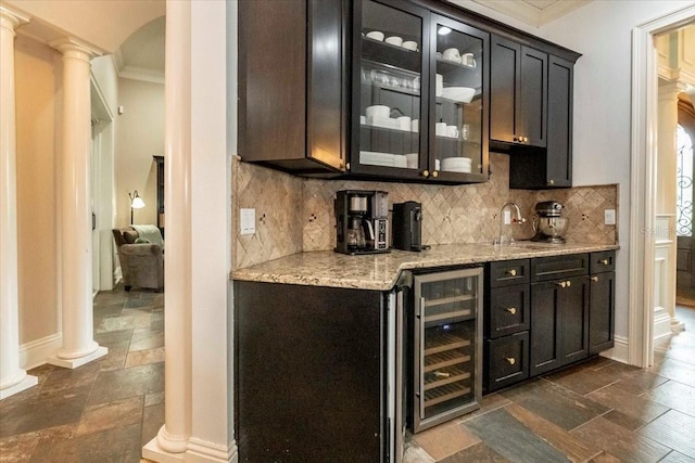 6357 Ashley Dr, Lakeland, FL 33813 - indoor bar with ornate columns, beverage cooler, stone tile floors, crown molding, and backsplash