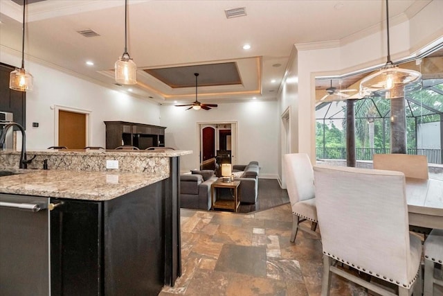6357 Ashley Dr, Lakeland, FL 33813 - kitchen featuring crown molding, a ceiling fan, a tray ceiling, light stone counters, and hanging light fixtures