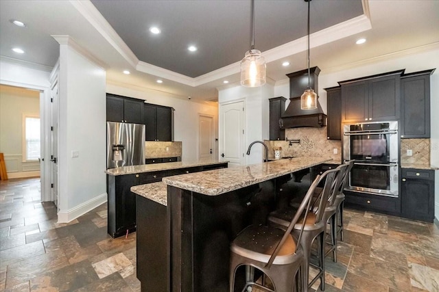 6357 Ashley Dr, Lakeland, FL 33813 - kitchen with a spacious island, custom exhaust hood, appliances with stainless steel finishes, a raised ceiling, and crown molding